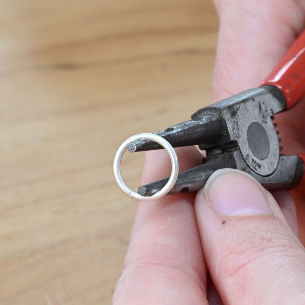Using ring opening pliers to create a paperclip chain link