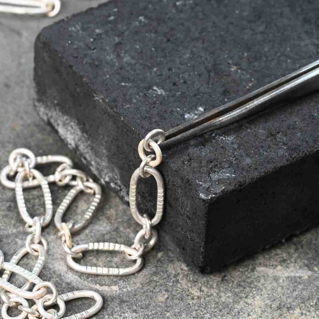 Holding a sterling silver chain in cross locking tweezers for soldering