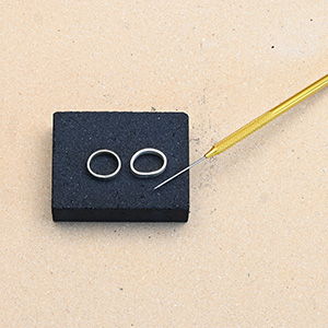 Charcoal block for soldering jewelry with solder pick and two rings ready for soldering